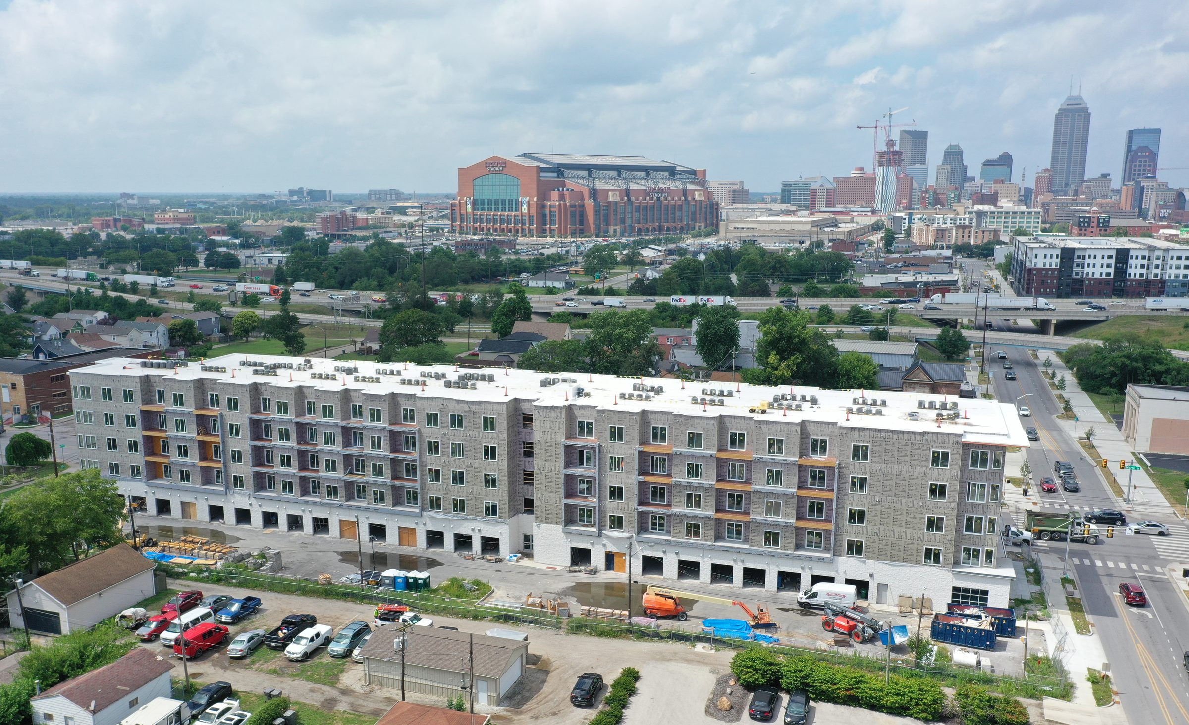 Active multifamily under construction in Indianapolis — wrap stage, downtown skyline beyond